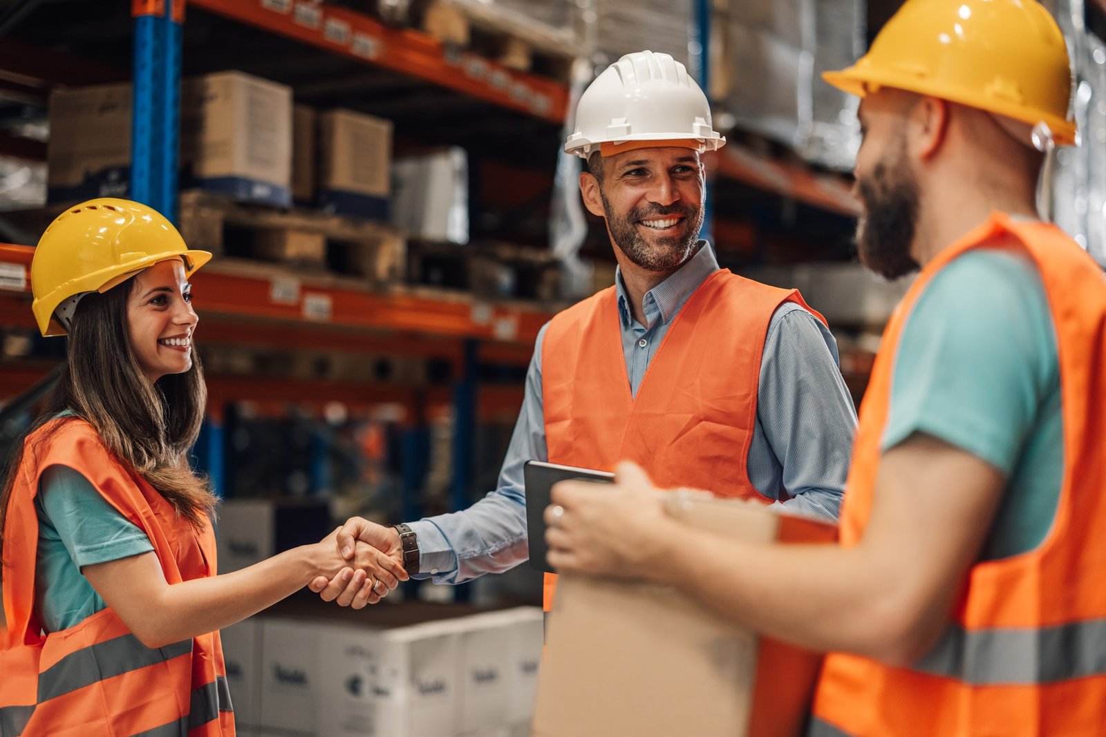 Diverse colleagues celebrate successful partnership in warehouse